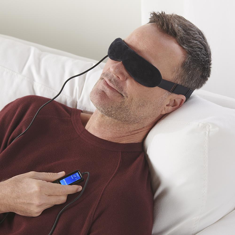 Man relaxing on couch using Wizard Research heated eye mask with handheld digital controller for dry eye relief